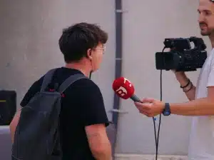 Un periodista graba con una cámara de video mientras entrevista a un joven en la calle