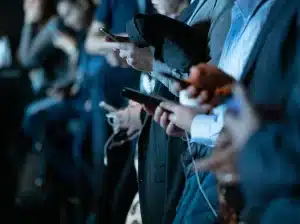 Fila de personas en un evento revisando las redes en su celular